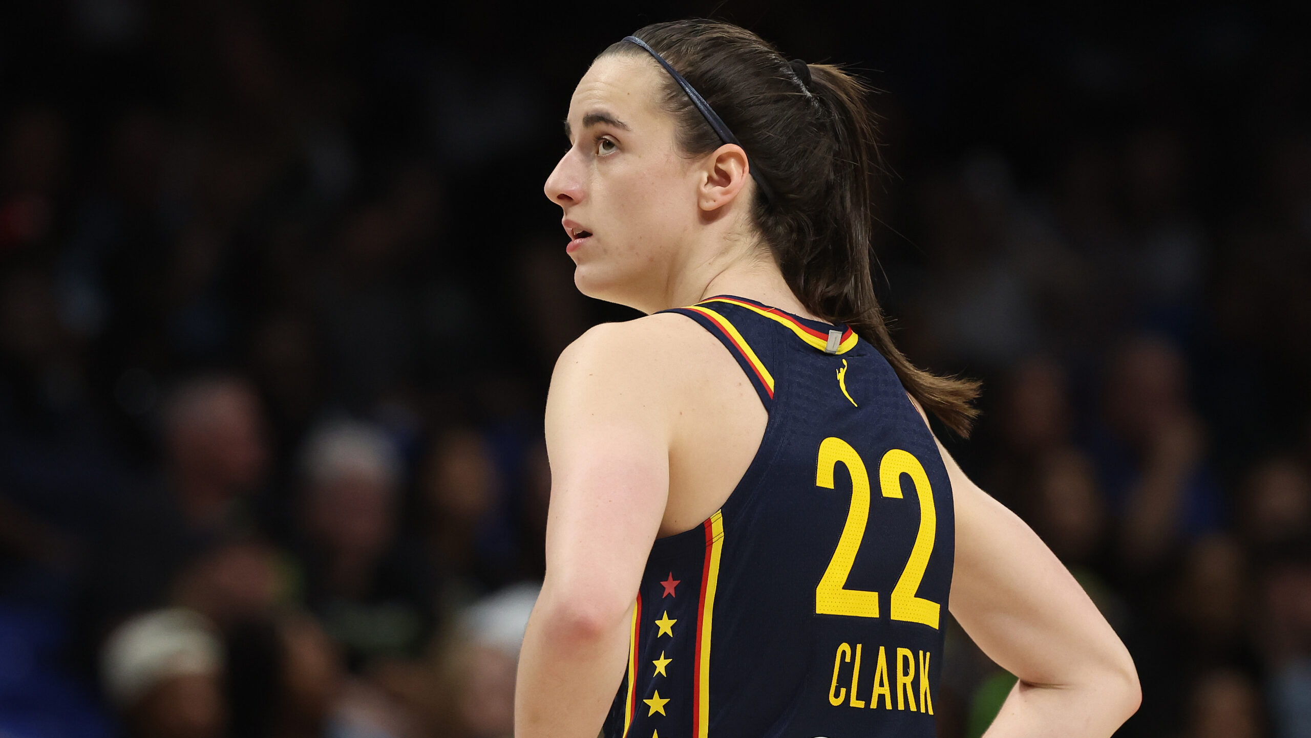 Caitlin Clark wearing an Indiana Fever jersey number 22, looking over her shoulder during a WNBA game.