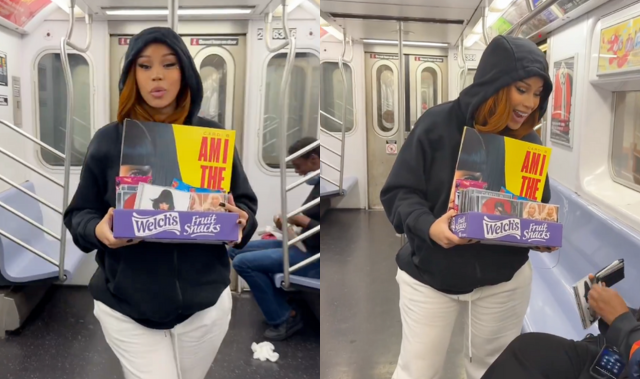 Cardi B in a black hoodie and white pants holding a box with her Am I The Drama album while interacting with passengers on the NYC subway.