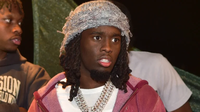 Kai Cenat wearing a knit beanie, hoodie, and multiple diamond chains at Union Square in New York City.