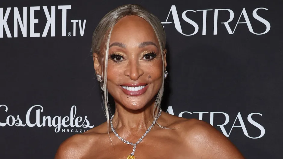 Karen Huger smiling on the red carpet wearing a strapless gown with diamond jewelry.