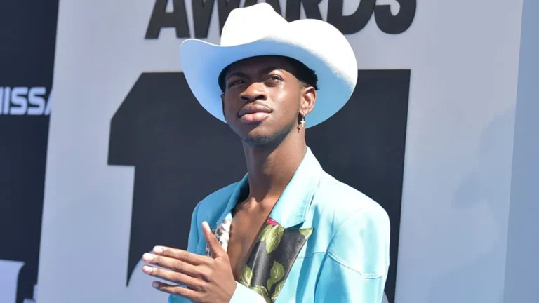 Lil Nas X wearing a white cowboy hat and turquoise jacket on the BET Awards red carpet.