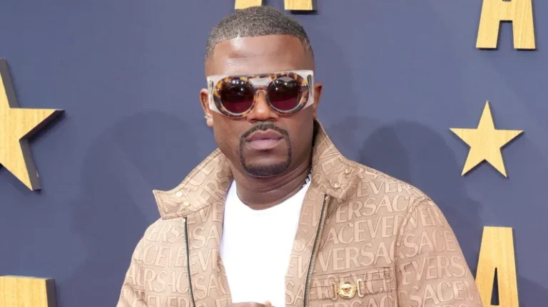 Ray J wearing a tan Versace jacket and oversized sunglasses on the red carpet.