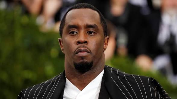 Sean Diddy Combs wearing a black pinstripe suit and white shirt at a red carpet event in 2025.