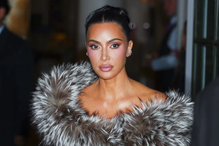 Kim Kardashian wearing a glamorous fur outfit, posing confidently at a red carpet event.