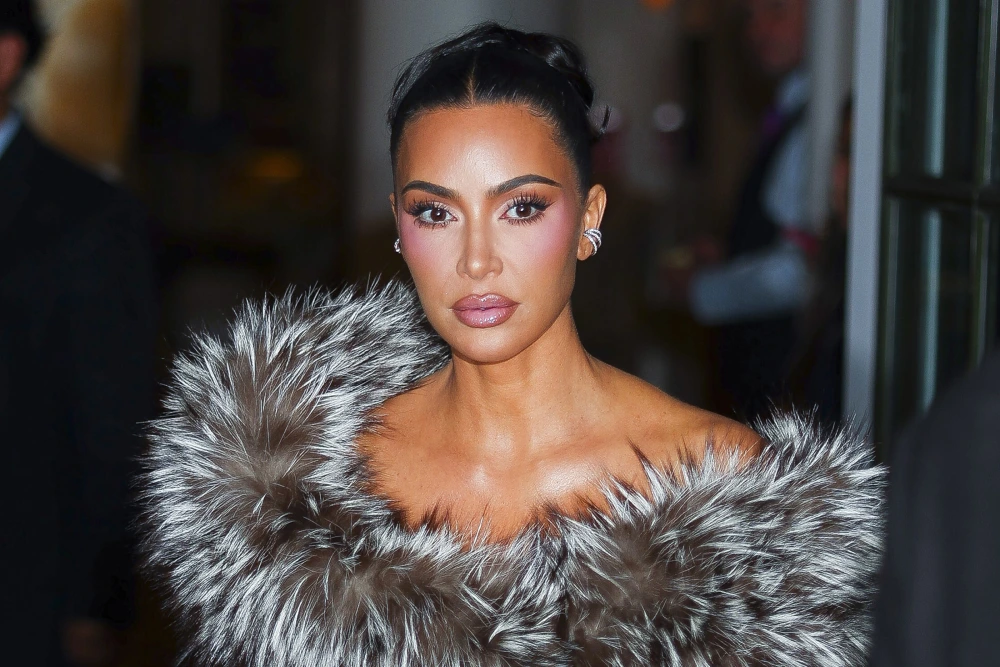 Kim Kardashian wearing a glamorous fur outfit, posing confidently at a red carpet event.