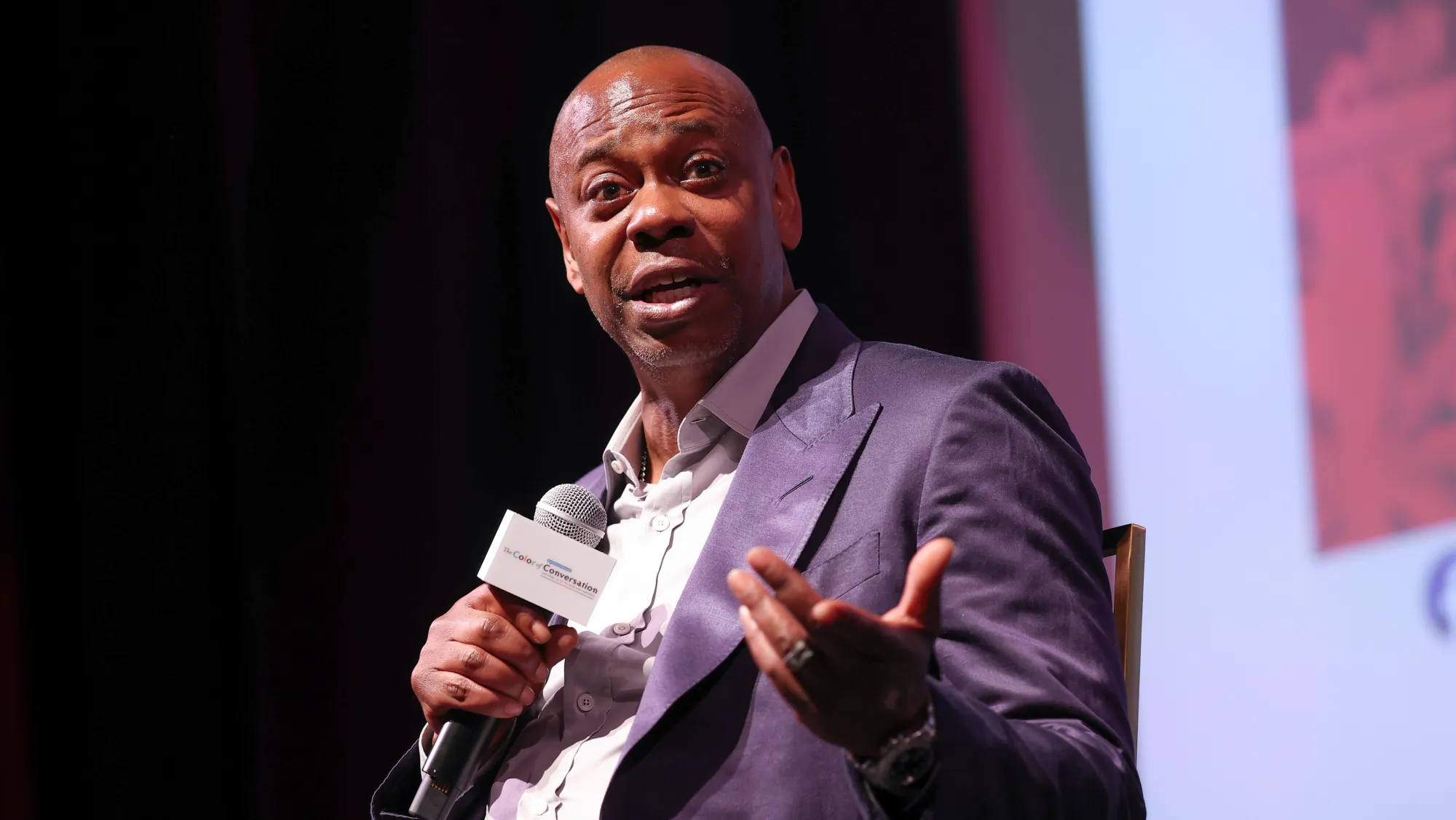 man on stage in suit talking